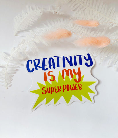 Sticker with white background that reads “creativity is my super power” in colorful letters over a bright green burst shape